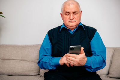 Man using mobile phone while sitting on sofa at home