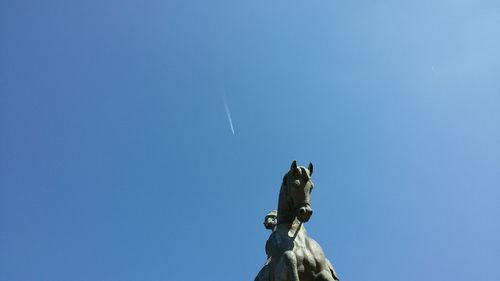 Low angle view of horse statue against blue sky