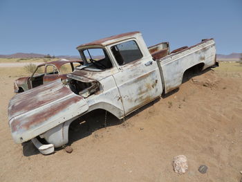 Abandoned car on field against clear sky