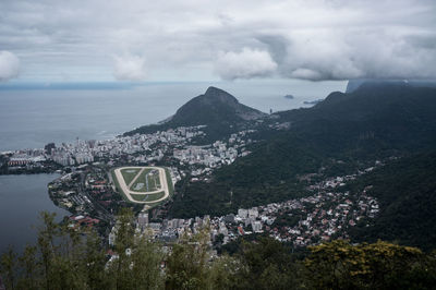 High angle view of city at waterfront against cloudy sky