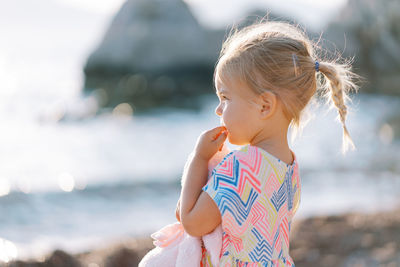 Side view of girl looking away while standing at beach