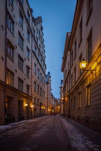 Street amidst buildings against sky at dusk