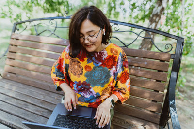 Female professional enjoys remote work on calm sunny day in lush green park