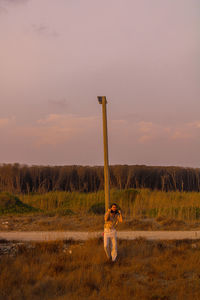 Man standing on field against sky during sunset