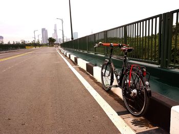 Bicycle on road against sky in city