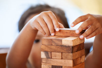 Girl playing with wooden toy blocks while sitting in porch