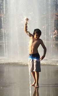 Full length of shirtless boy standing at beach