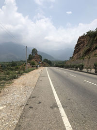 Road leading towards mountains against sky