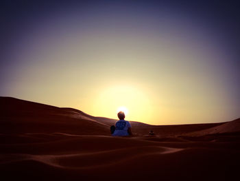 Full length of man on desert against sky during sunset