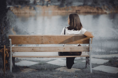 Rear view of woman sitting on bench