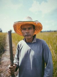 Portrait of man wearing hat standing on field