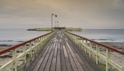 Pier over sea against sky during sunset