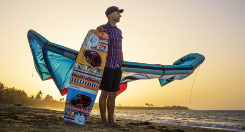 Man on beach against clear sky during sunset