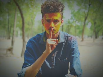 Portrait of young man with powder paint keeping finger on lips