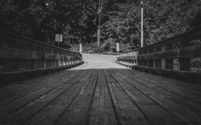 Surface level of wooden footbridge along trees