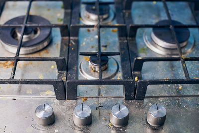 Dirty gas stove top with food leftovers. unclean steel kitchen cooktop with greasy spots