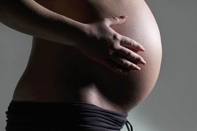 Side view of woman touching hair over black background