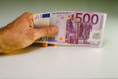 Close-up of hand holding paper currency on table