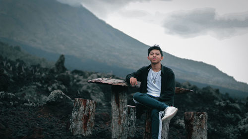 Man sitting on rock against mountains