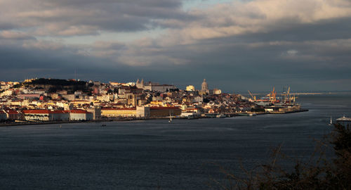 Buildings by sea against sky at dusk