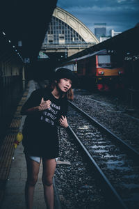 Young woman with backpack standing on railroad station platform