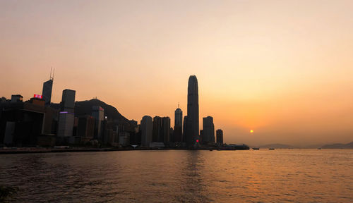 Scenic view of sea and buildings against sky during sunset,hong kong