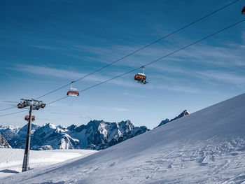 Overhead cable car over snowcapped mountains against sky