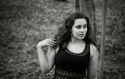 Teenage girl standing by tree trunk in forest