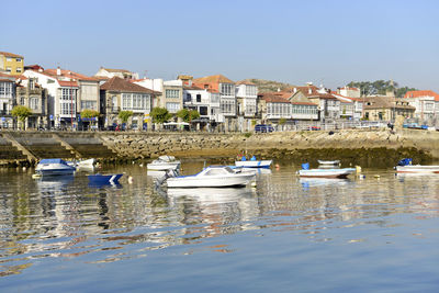 Sailboats moored on canal by buildings against clear sky