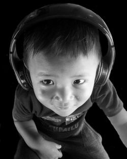 Portrait of cute boy wearing headphones over black background