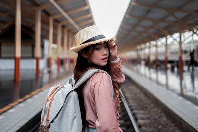 Portrait of young woman looking away while sitting on railroad track