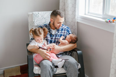 Man sitting with daughters on chair at home