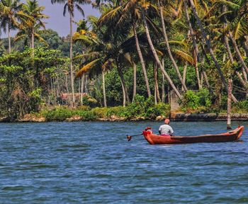 People in boat on sea against trees