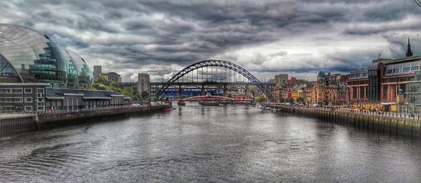 Bridge over river against cloudy sky