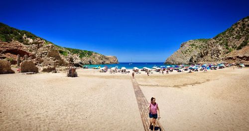 Panoramic view of people on beach against clear blue sky