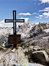 Cross on rock against sky