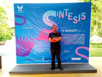 Full length portrait of young man standing against blue sign