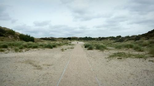 Road passing through landscape against cloudy sky