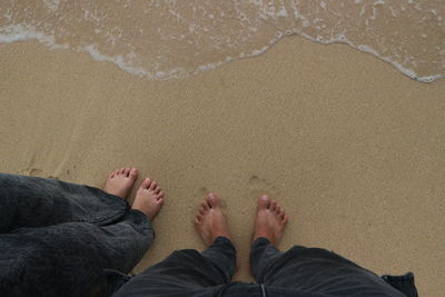 Low section of man standing on beach