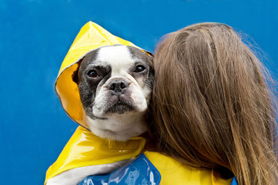 Woman with dog against blue wall