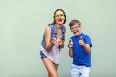 Woman and boy with eyeglasses gesturing against green background