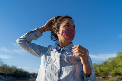 Portrait of young woman holding umbrella against blue sky