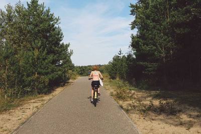 Rear view of woman cycling on footpath