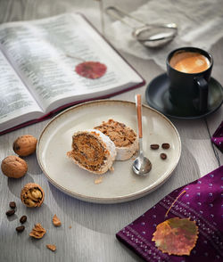 Tasty cake roll filled with walnuts and coffee on wooden table