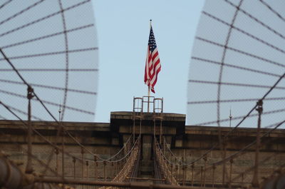 The united states flag on top of brooklyn bridge.