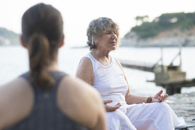 Senior woman doing a yoga exercise at the coast