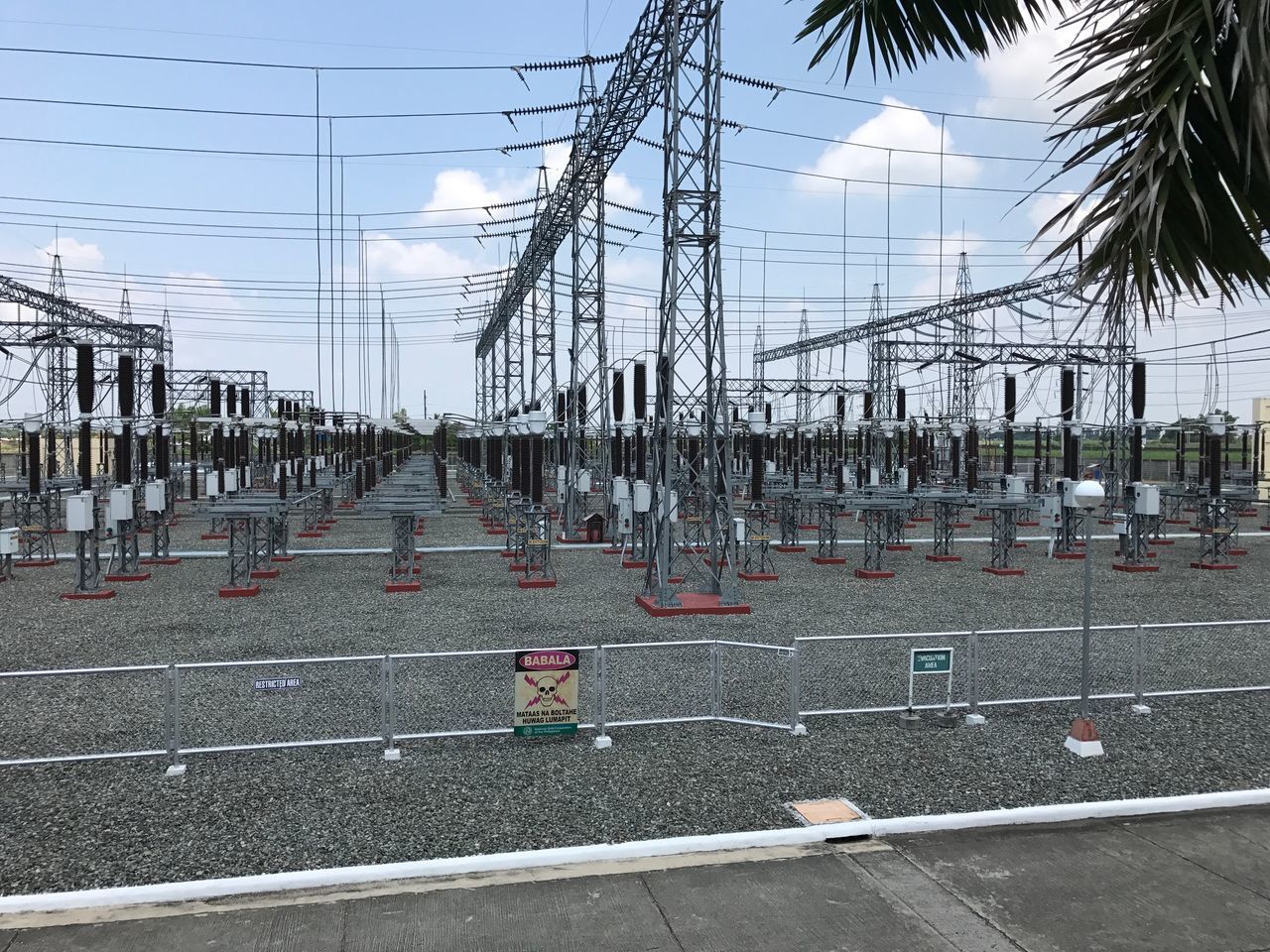 ELECTRICITY PYLONS ON ROAD AGAINST SKY