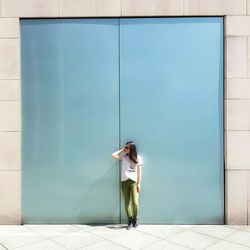 Full length of woman standing against wall