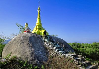 Burmese srupa on a rock with guardian dog and blue sky