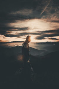 Man standing on mountain against sky during sunset